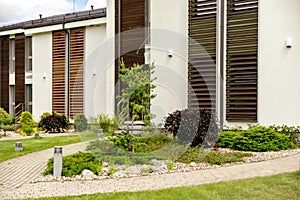 Various plants and stones in front of modern house, front yard. Landscape design. Beautiful garden. Modern urban living