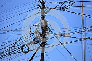 Various power lines, signal cables, telephone lines, internet interconnects on electrical poles, blue sky background.