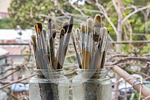 Various professional paint brushes in the transparent jar