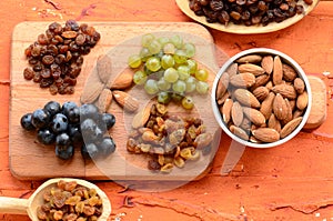 Various raisins, vine berries and almonds on chopping board