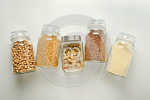 Various raw cereals in glass jar. Zero waste concept. Food storage. Flat lay. White background