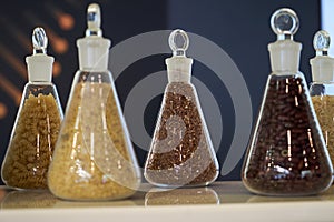 Various raw cereals, grains, beans and pasta for cooking healthy food in glass jars on a wooden shelf.