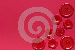 Various red sewing buttons on red background