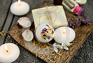 Various relaxation bath products on natural wood tray: creamy bath bomb  bar of soap and aroma oil bottles.