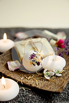 Various relaxation bath products on natural wood tray: creamy bath bomb  bar of soap and aroma oil bottles.