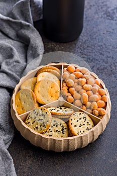 Various salty snacks in a round bowl on black table