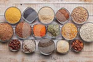 Various seeds, grains and nuts on old table - in bowls, top view