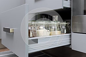 Various seeds in storage jars in hutch, white modern kitchen in background. Smart kitchen organization