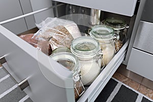 Various seeds in storage jars in hutch, white modern kitchen in background. Smart kitchen organization