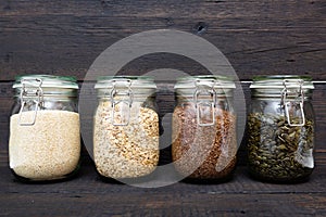 Various seeds in storage jars in pantry, dark wooden background. Smart kitchen organization