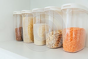 Various seeds in storage jars in pantry, white modern kitchen in background. Smart kitchen organization. Healthy cooking, clean