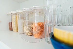 Various seeds in storage jars in pantry, white modern kitchen in background. Smart kitchen organization. Healthy cooking, clean