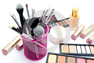 Various set of professional makeup brushes and cosmetics and palette of colourful eye shadows isolated