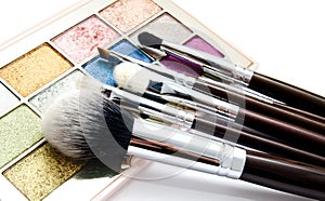 Various set of professional makeup brushes and palette of colourful eye shadows isolated