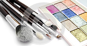 Various set of professional makeup brushes and palette of colourful eye shadows isolated