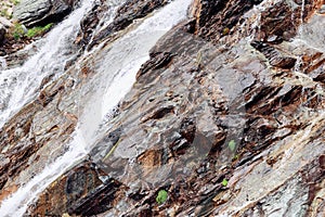 Various shades of brown with small areas of emerald moss and foam jets of an alpine waterfall