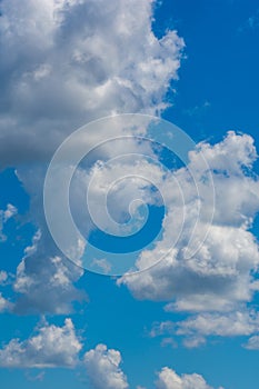 Various shape fluffy cummulus clouds accumulating on blue summer sky