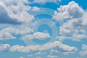 Various shape fluffy cummulus clouds accumulating on blue summer sky