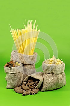 Various Shapes of Pasta In Jute Bags on Green