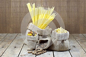 Various Shapes of Pasta In Jute Bags on Wooden Planks