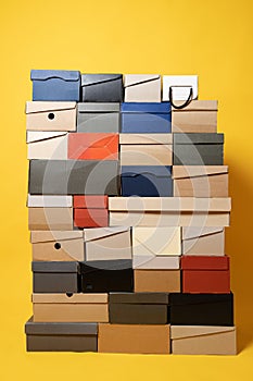 Various shoe boxes are stacked on a yellow background. Copy space. Sale concept.