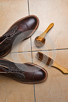 Various Shoes Cleaning Accessories for Dark Brown Grain Brogue Derby Boots Made of Calf Leather Over Tile Background