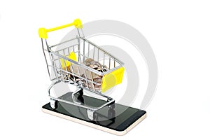 Various silver money coins in yellow mini shopping cart or supermarket trolley setting on smartphone isolated on white background.