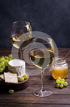 Various sorts of cheese, grapes and two glasses of the white wine