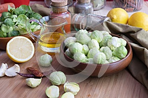 Various spices, oil, sliced lemon on a board, peeled Brussels sprouts lies in a wooden bowl