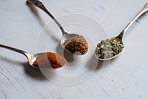 Various spices in spoons on white wood table background. Center arrangementn