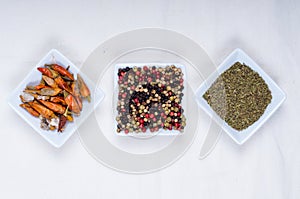 various spices in white bowls of square shape in white background