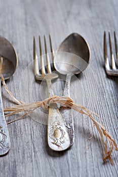 Various spoons and forks entwined on rustic wooden table