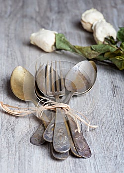 Various spoons and forks entwined on rustic wooden table