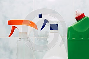 Various spray bottles with detergent on the background of tiles in the bathroom