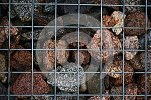 Various stones behind a metal grate after rain