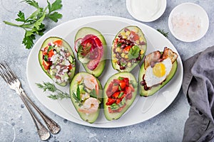 Various stuffed avocadoes on  white plate