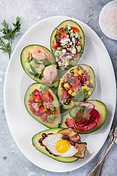 Various stuffed avocadoes on  white plate