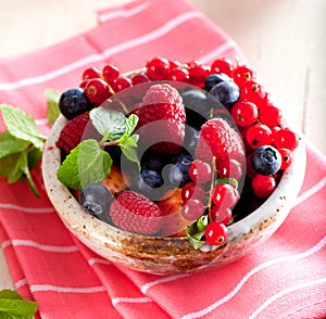 Various summer fruits in a bowl. Assorted fresh berries with lea