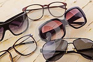 Various sunglasses set on yellow wooden background.