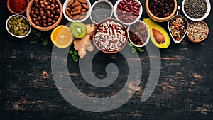 Various superfoods. Dried fruits, nuts, beans, fruits and vegetables. On a black wooden background.