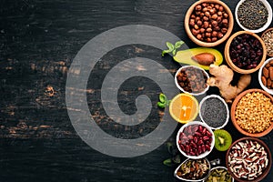 Various superfoods. Dried fruits, nuts, beans, fruits and vegetables. On a black wooden background.