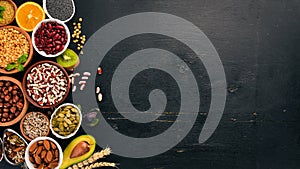 Various superfoods. Dried fruits, nuts, beans, fruits and vegetables. On a black wooden background.