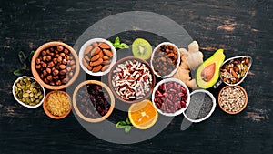 Various superfoods. Dried fruits, nuts, beans, fruits and vegetables. On a black wooden background.