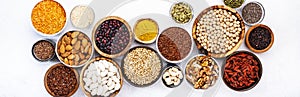 Various superfoods, legumes, cereals, nuts, seeds in bowls on white background. Superfood as chia, spirulina, beans, goji berries