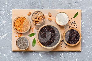 Various superfoods in smal bowl on colored background. Superfood as rice, chia, quinoa, lentils, nuts, sesame seeds