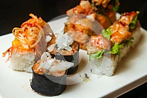 Various sushi rolls with delicacy decoration served on a white flat tray