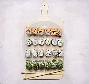 Various sushi sets, dill, salmon, crab on a white cutting board Asian food on wooden rustic background top view close up