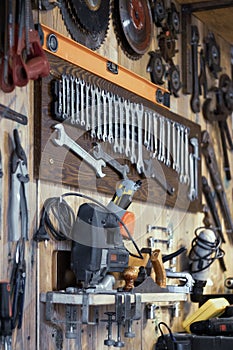 Various tools hang on a wooden wall in a workshop