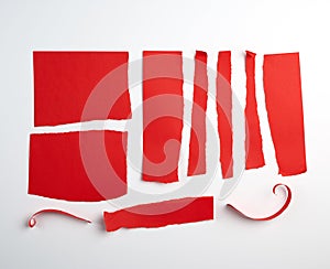 various torn strips of red paper on a white background