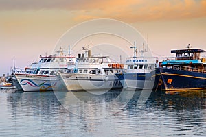 Various touristic ships and pleasure boats in the harbor at sunset. Sea port illustration